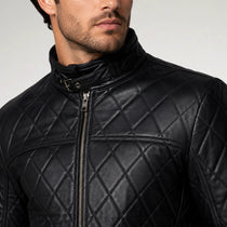 Close-up of a man wearing a black quilted leather jacket with a high stand-up collar and front zipper, against a light gray studio background.