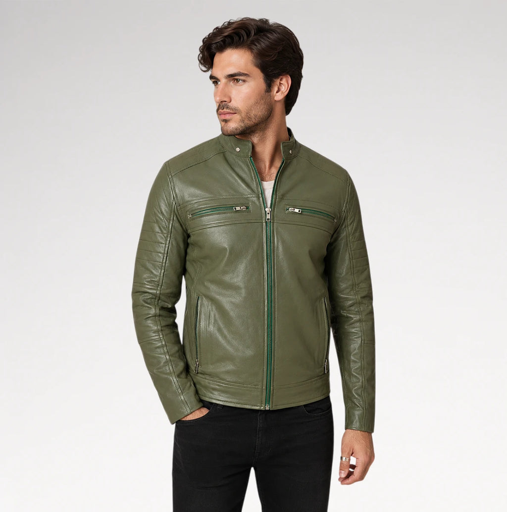 A man wearing an olive green leather jacket with a full zip and zippered chest pockets, paired with black pants, photographed against a light gray studio background.