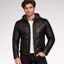 A man wearing a black leather hooded biker jacket with quilted shoulder panels, zippered chest pockets, and a white t-shirt underneath, photographed against a light gray studio background.