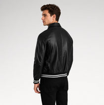 A man wearing a black leather bomber jacket with white stripe details on the cuffs and hem, shown from a side-back angle against a light gray studio background.