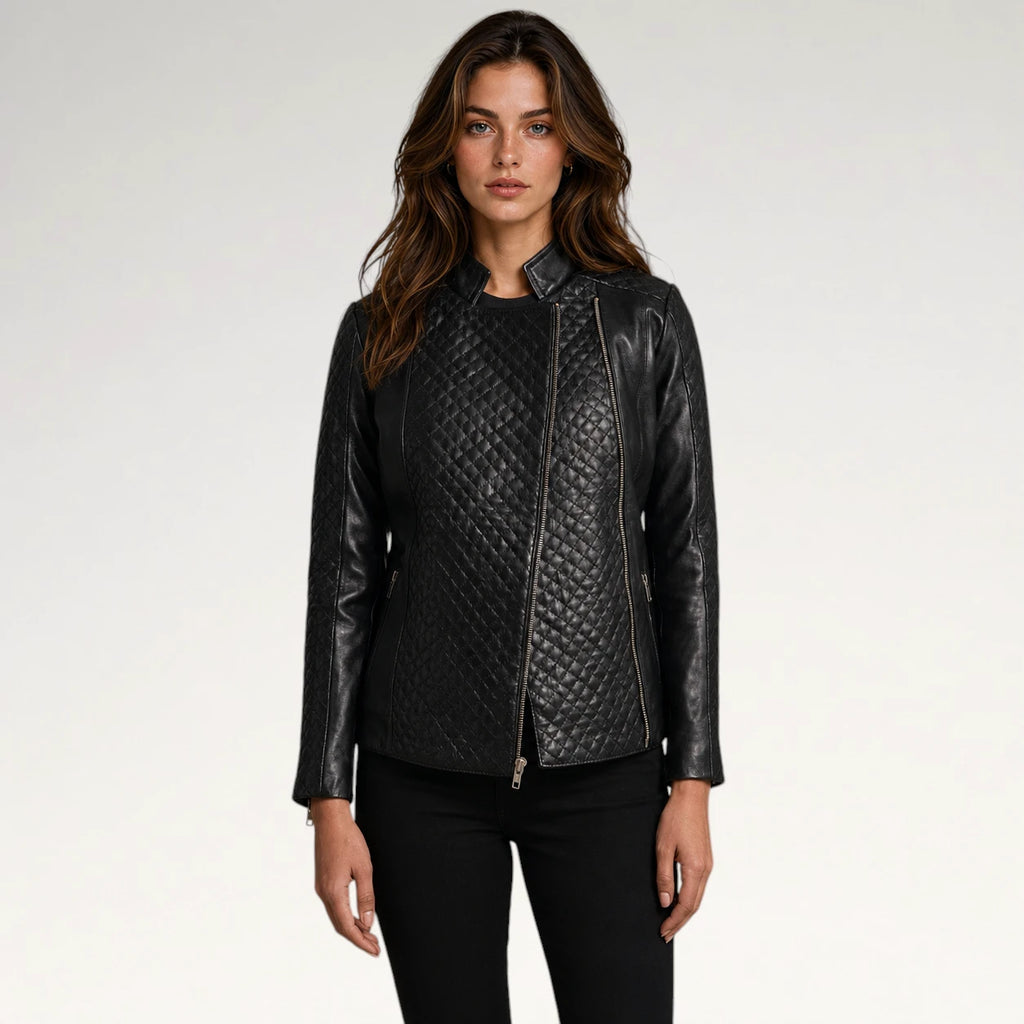A woman modeling a black faux-leather moto jacket with quilted diamond-patterned front panels and smooth leather sleeves, paired with black pants, against a light gray studio background.