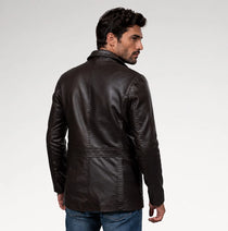 A man wearing a dark brown leather jacket, shown from a three-quarters back view against a light gray studio background.