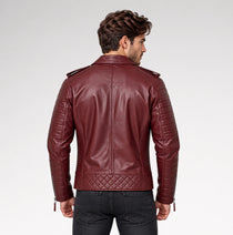 A man viewed from the back wearing a burgundy leather motorcycle jacket with quilted paneling and zippered sleeves, paired with dark jeans against a light gray studio background.