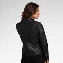 A woman shown from the back wearing a black quilted leather jacket against a plain light gray studio background.
