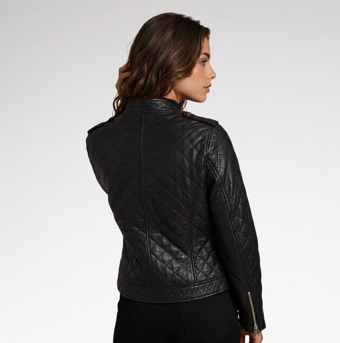 A woman shown from the back wearing a black quilted leather jacket against a plain light gray studio background.
