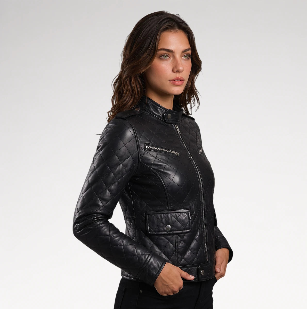 A woman modeling a black quilted leather moto jacket with silver zippers, photographed against a clean light gray studio background.
