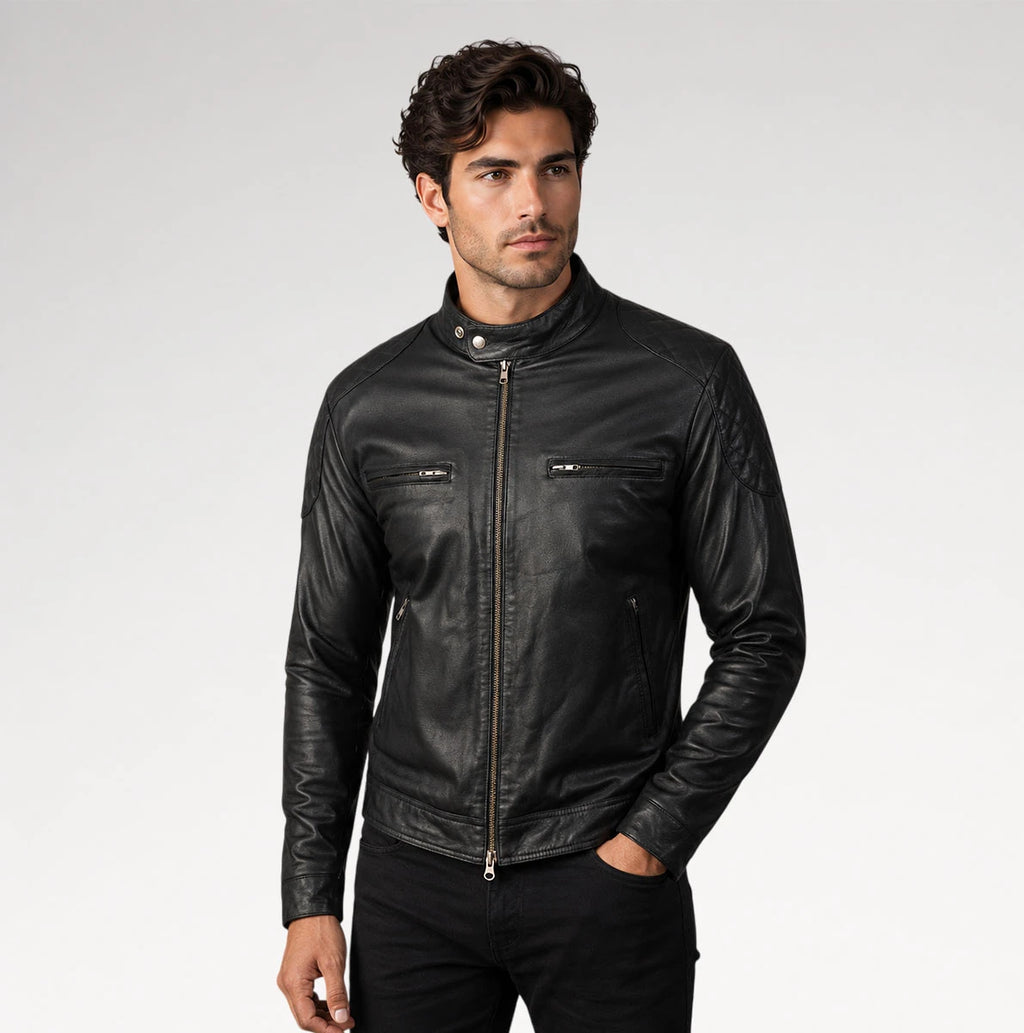 A man wearing a black leather motorcycle jacket with a stand collar, front zipper, and zippered chest pockets, photographed against a light gray studio background.