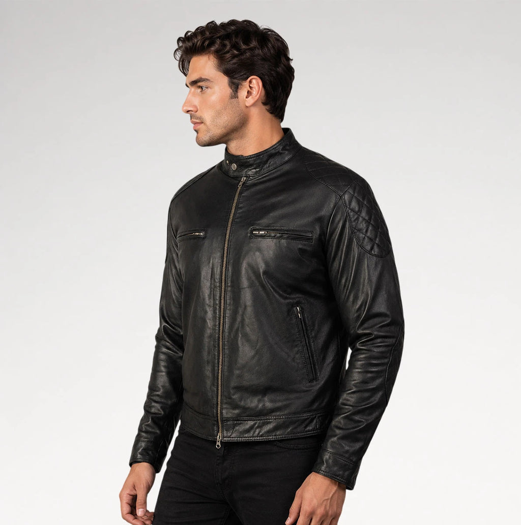 A man wearing a black leather motorcycle jacket with quilted shoulder detailing, shown in profile against a light gray studio background.