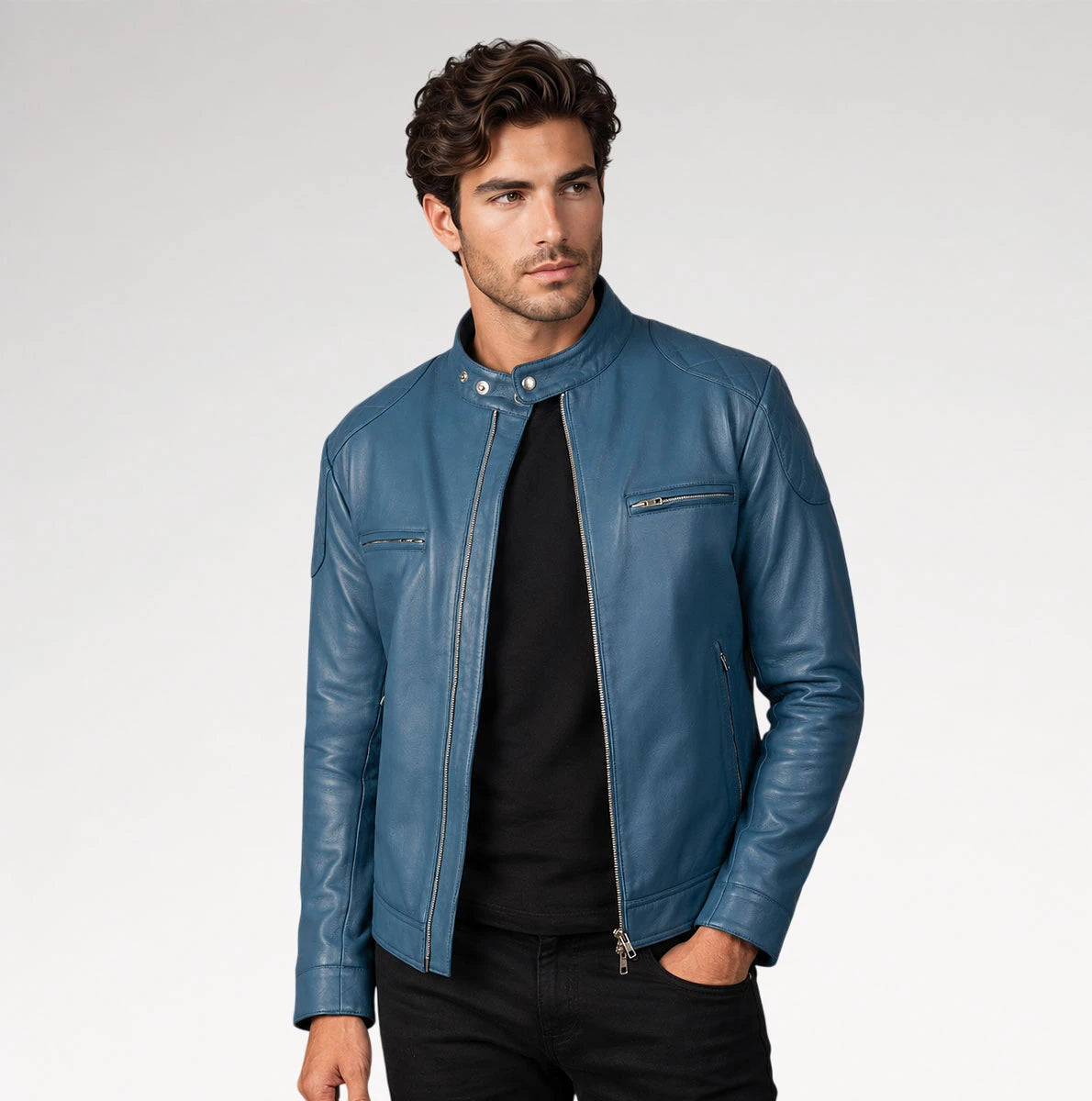 A man wearing a blue leather moto jacket over a black t-shirt and black pants, standing against a light gray studio background. Main image