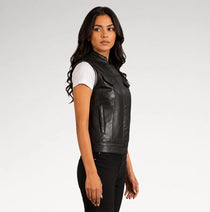 A woman modeling a black leather sleeveless vest over a white t-shirt and black pants, photographed against a light gray studio background.