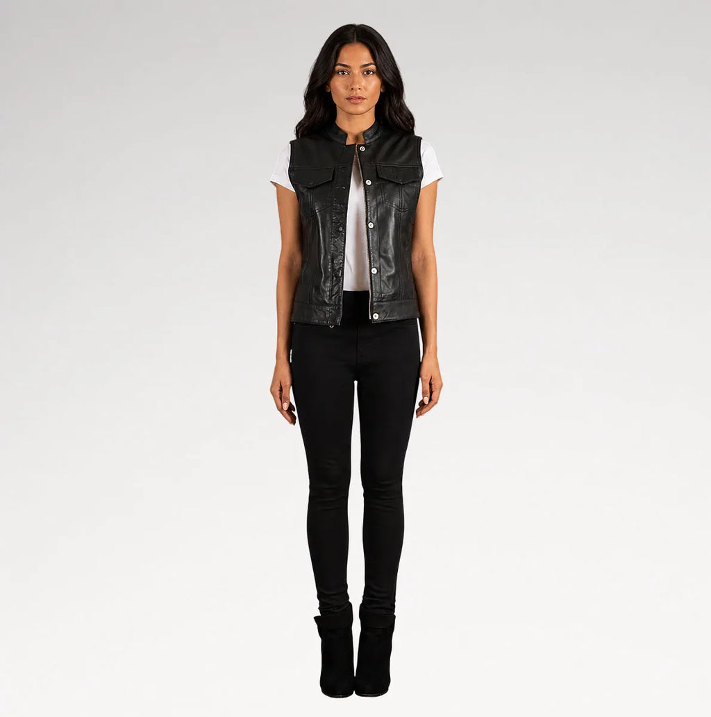 A woman modeling a black leather sleeveless vest over a white t-shirt and black skinny jeans, standing against a light gray studio background.
