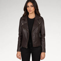 A woman modeling a dark brown faux-leather moto jacket with silver snap and zip details, worn over a black top and black pants against a light gray studio background.