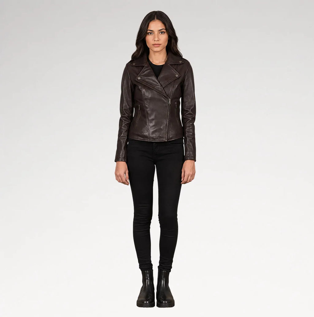 A woman modeling a dark brown leather moto jacket, paired with black skinny jeans and black ankle boots, against a light gray studio background.
