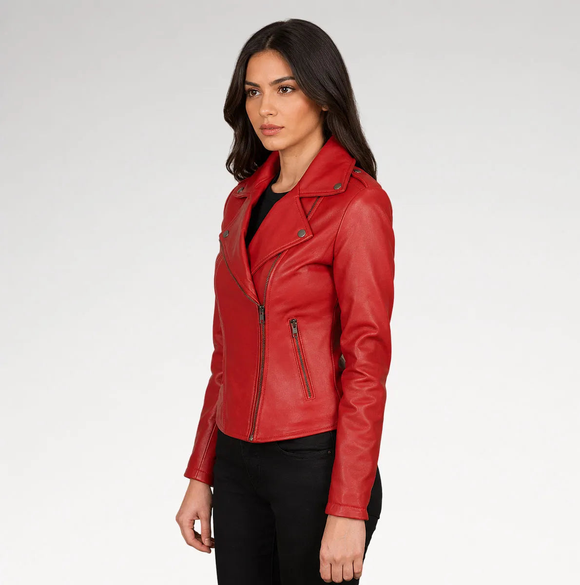 A woman modeling a red leather moto jacket with an asymmetrical zipper, set against a plain light gray studio background.