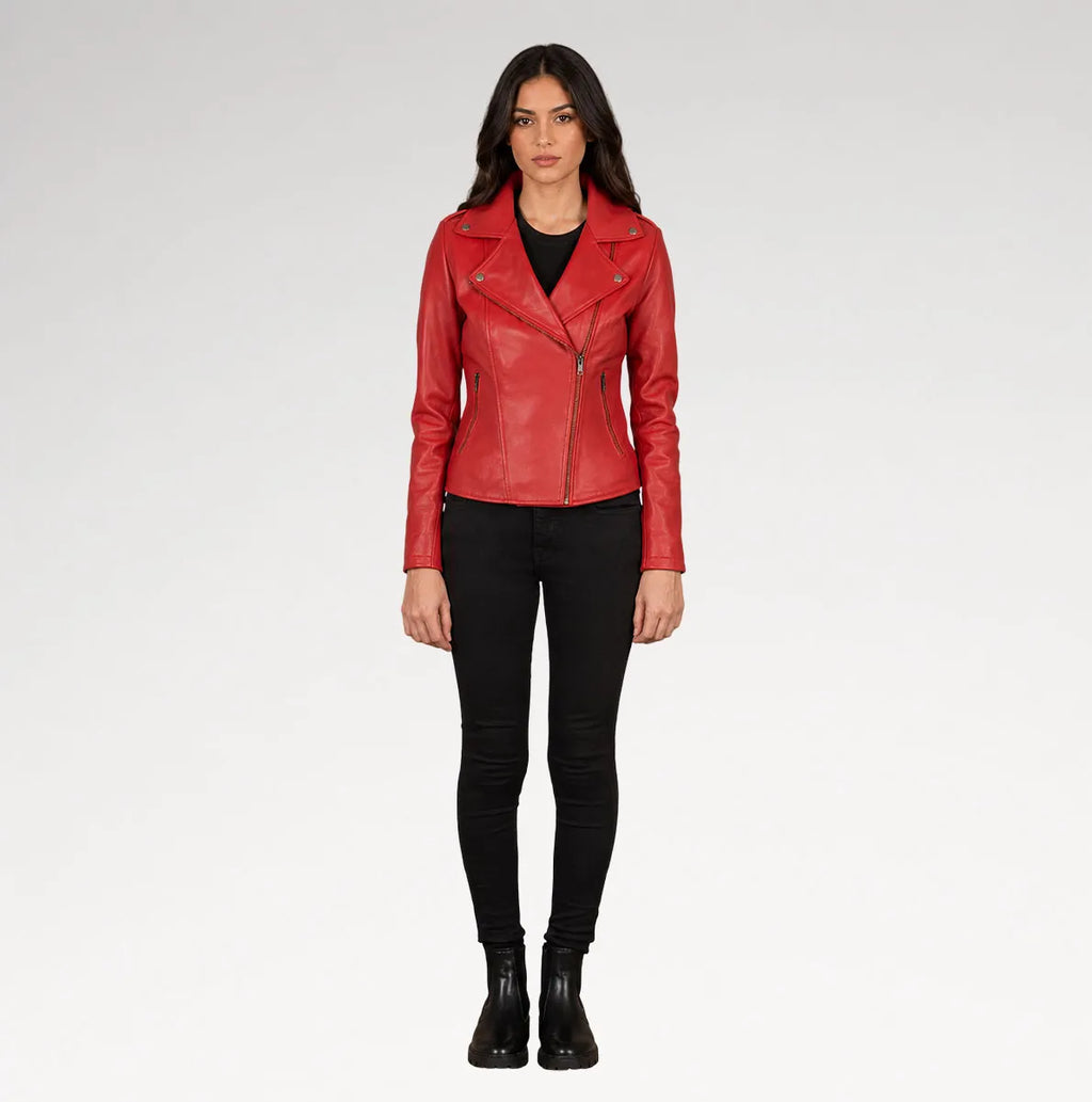 A woman modeling a red leather moto jacket over a black top and black skinny pants, standing against a light gray studio background.