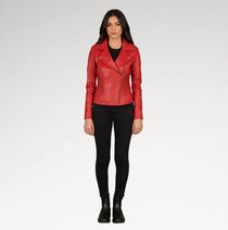 A woman modeling a red leather moto jacket over a black top and black skinny pants, standing against a light gray studio background.