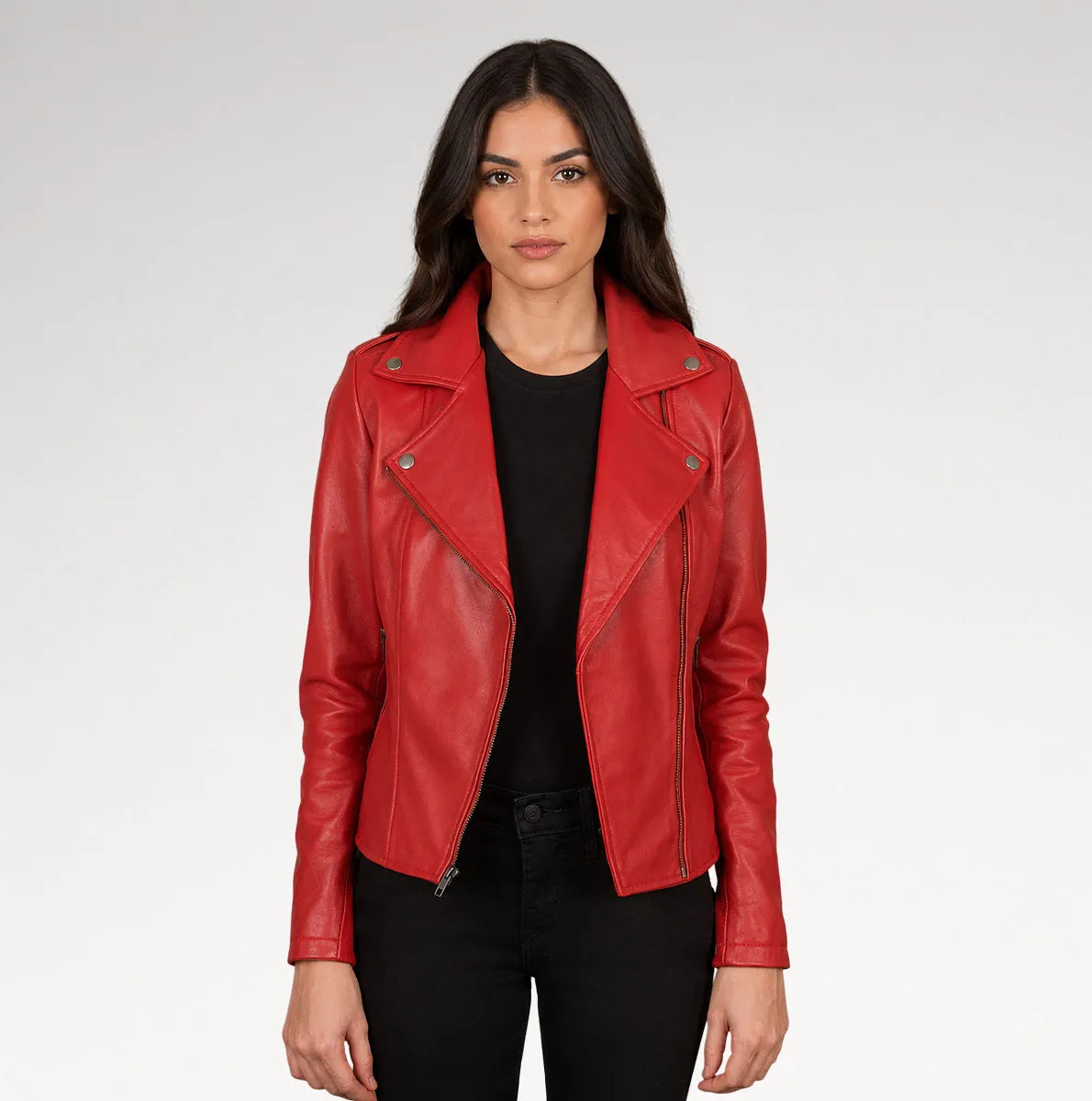 A woman modeling a bright red leather moto jacket over a black top and black pants, photographed against a light gray studio background.