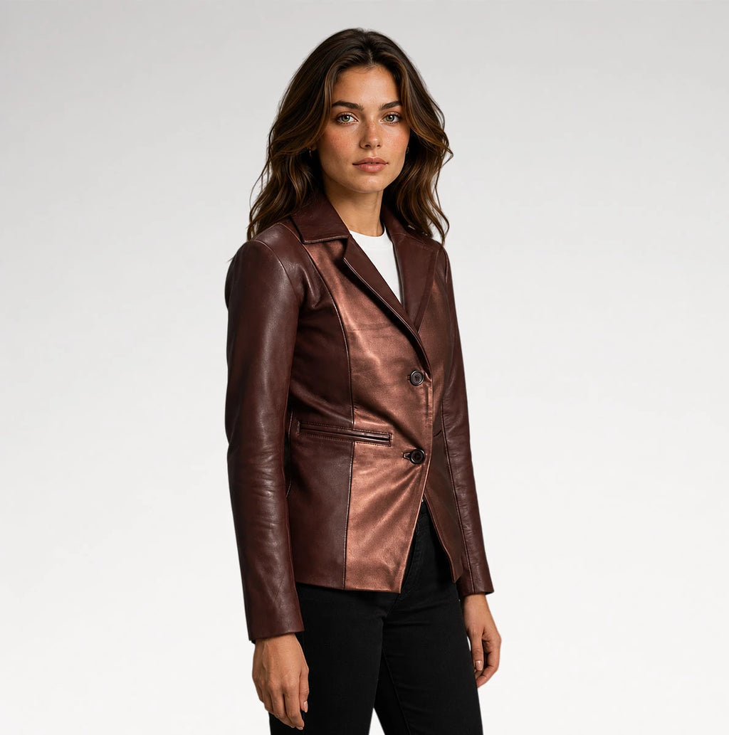 A woman modeling a metallic bronze-brown leather blazer with black pants, photographed against a clean light gray studio background.