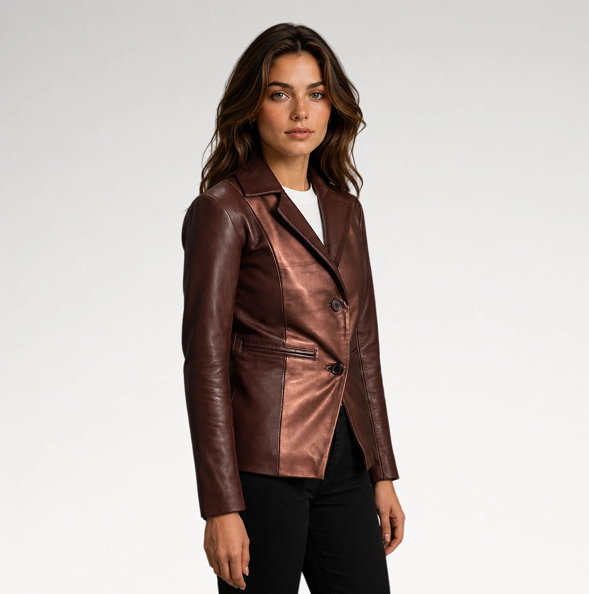 A woman modeling a metallic bronze-brown leather blazer with black pants, photographed against a clean light gray studio background.