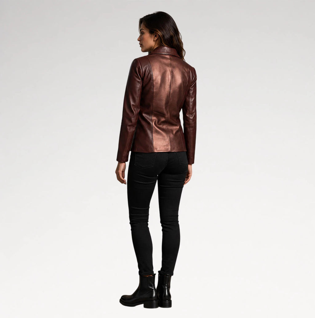 A woman is shown from the back wearing a metallic bronze-brown leather jacket, black skinny jeans, and black ankle boots against a plain light gray studio background.