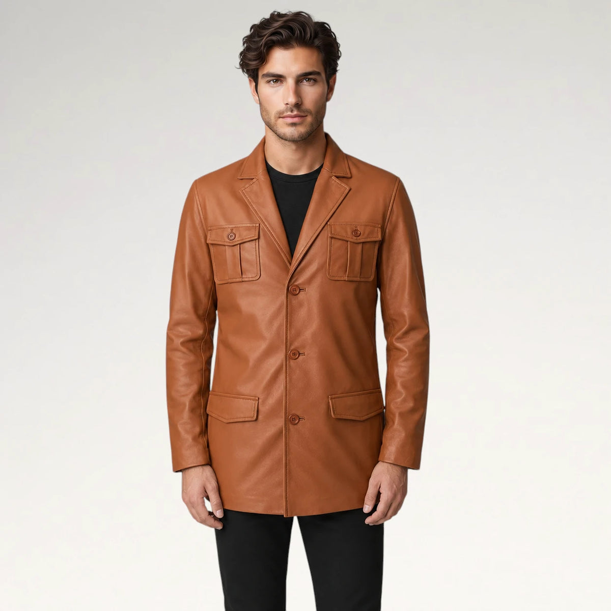 A man wearing a tan leather blazer with flap pockets over a black shirt and black pants, standing against a light gray studio background. Main image