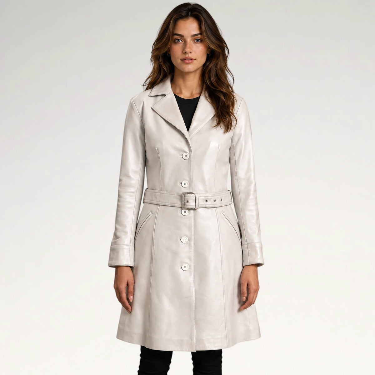 A woman modeling a light beige leather trench coat with a matching belt, worn over a black top and black pants, against a plain light gray studio background. Main image