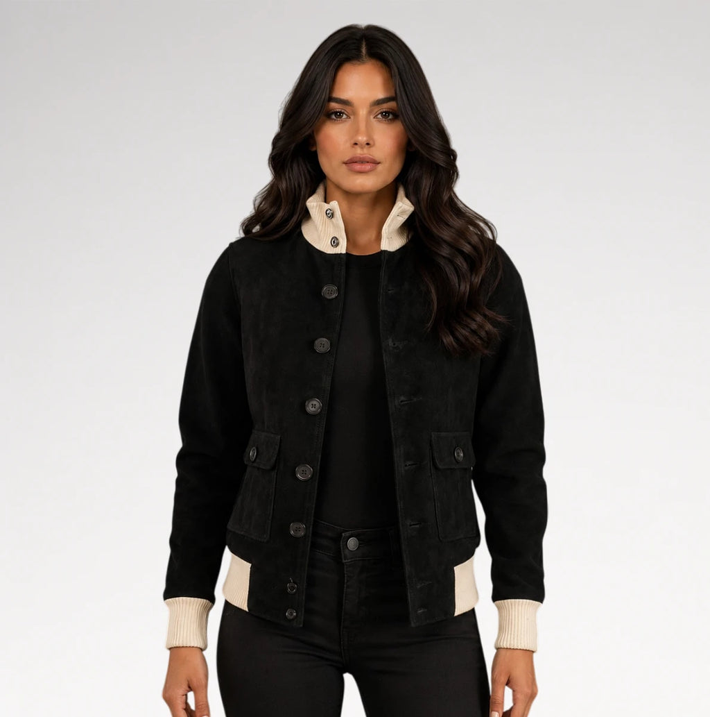 A woman modeling a black corduroy jacket with cream ribbed collar, cuffs, and hem, paired with black pants against a light gray studio background.