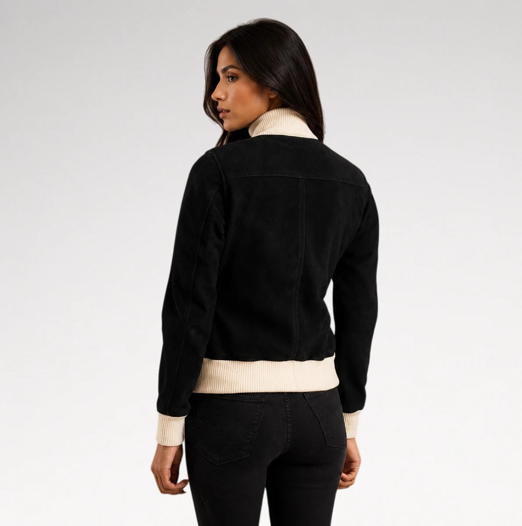 A woman shown from the back wearing a black suede-like jacket with contrasting cream ribbed trim at the collar, cuffs, and hem, paired with black jeans against a light gray studio background.
