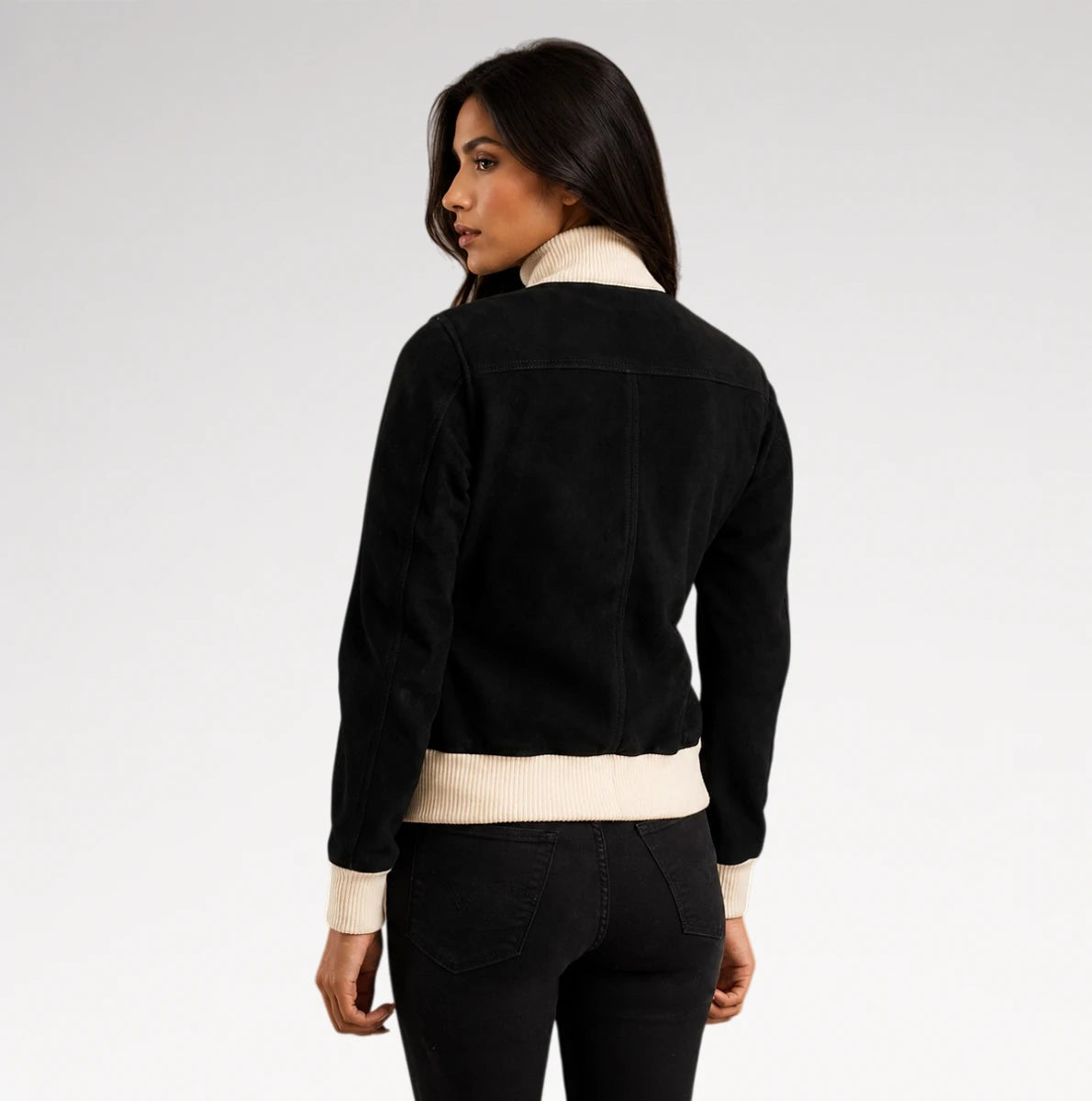 A woman shown from the back wearing a black suede-like jacket with contrasting cream ribbed trim at the collar, cuffs, and hem, paired with black jeans against a light gray studio background.