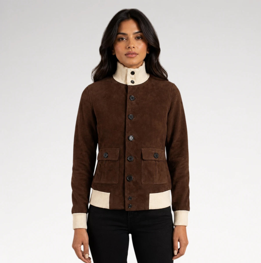 A woman modeling a brown suede jacket with cream ribbed trim at the mock neck, cuffs, and hem, paired with black pants against a light gray studio background.