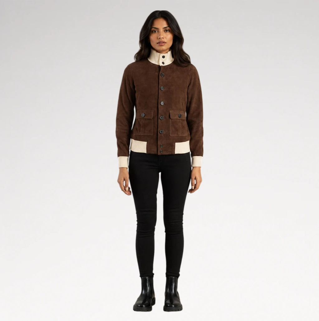 A woman modeling a brown suede jacket with cream ribbed trim and a high cream collar, paired with black pants and black boots, against a light gray studio background.