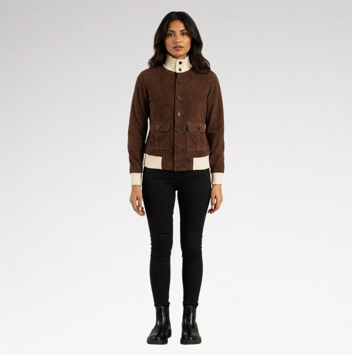 A woman modeling a brown suede jacket with cream ribbed trim and a high cream collar, paired with black pants and black boots, against a light gray studio background.