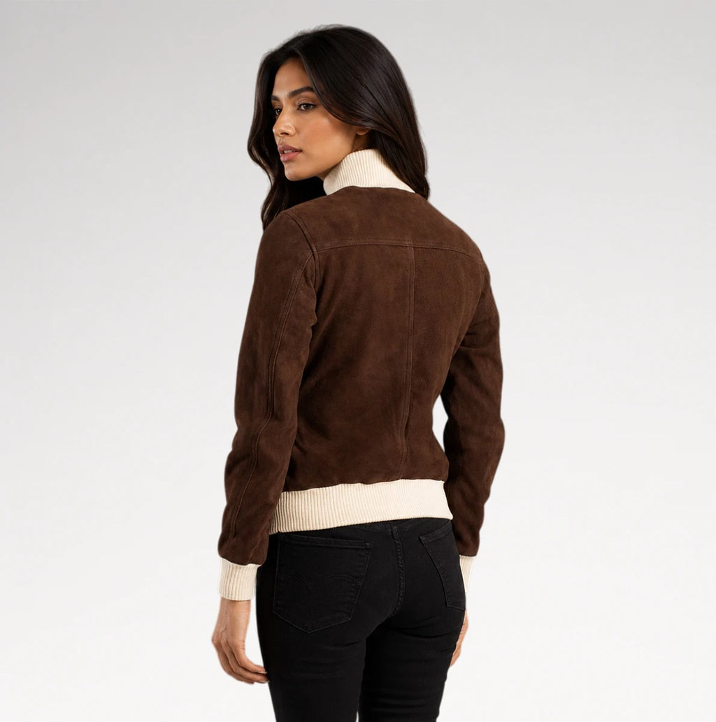A woman shown from the back wearing a brown suede bomber-style jacket with cream ribbed trim at the collar and hem, paired with black pants, against a light gray studio background.