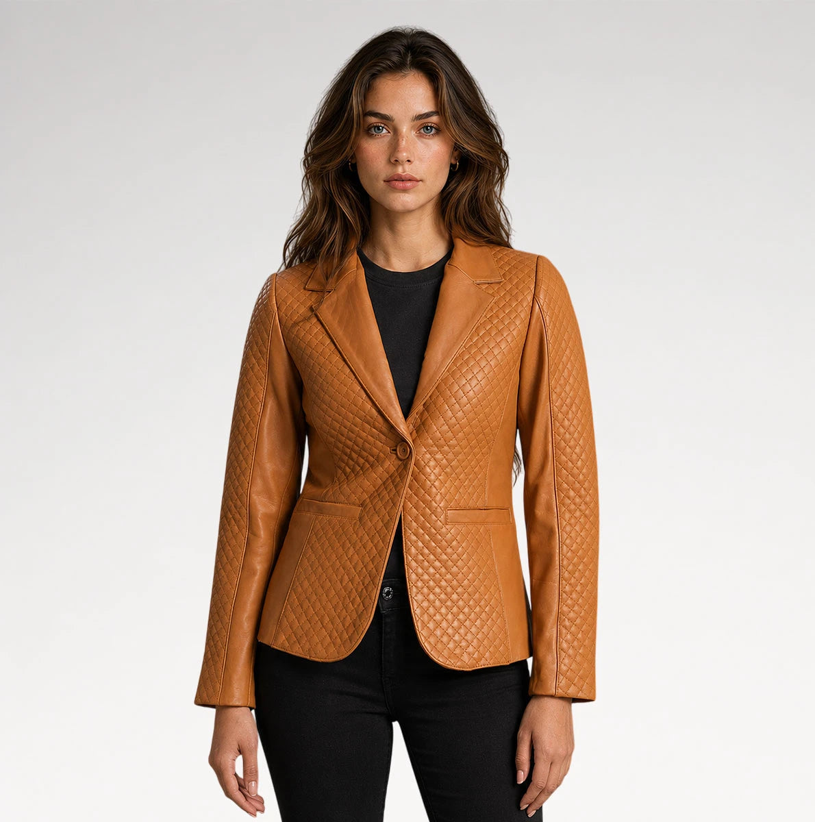 A woman modeling a tan textured leather blazer with a single button closure, notched lapels, and welt pockets, worn over a black top and black pants against a light gray studio background. Main image