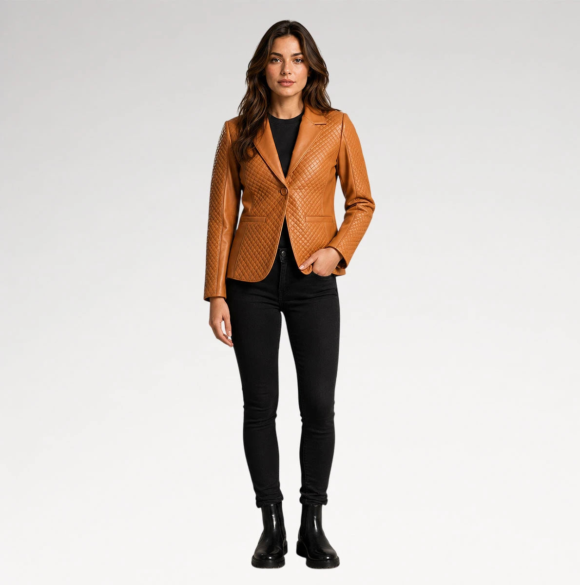 A woman modeling a tan quilted blazer over a black top and black skinny pants, standing against a light gray studio background.