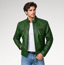 A man wearing a dark green quilted faux leather jacket over a white t-shirt and blue jeans, standing against a light gray studio background.