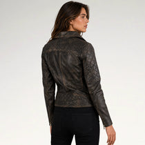 A woman wearing a dark brown quilted leather jacket, shown from a three-quarters back view against a light gray studio background.