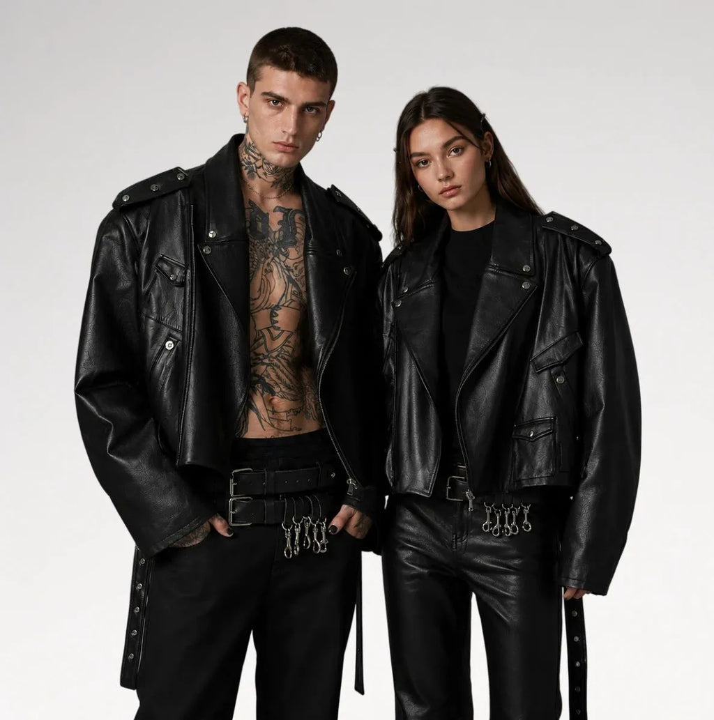 Two models wearing black leather motorcycle jackets and matching black leather pants with chain details, posed against a light gray studio background.