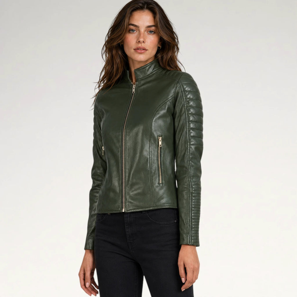 A woman modeling a dark olive green faux leather biker jacket with gold-tone zippers, paired with black jeans, against a plain light gray studio background.