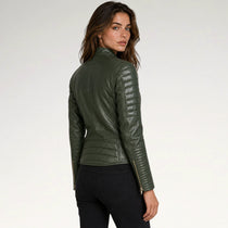 A woman wearing an olive green faux leather jacket with quilted sleeve panels and gold-tone zipper details, shown from a rear three-quarter view against a plain white studio background.