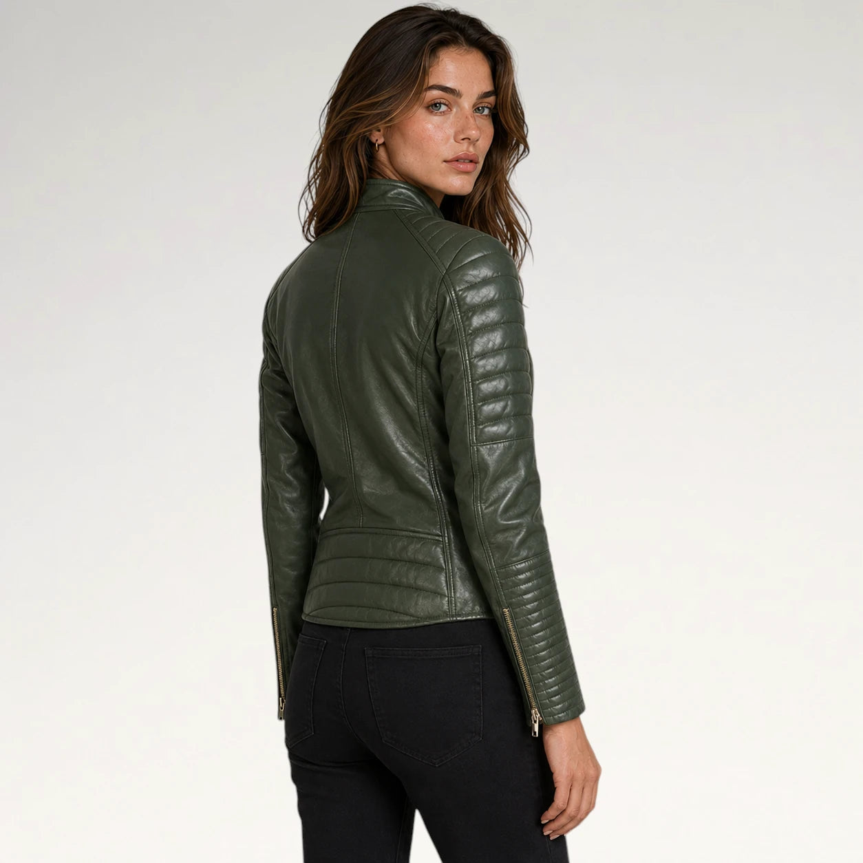 A woman wearing an olive green faux leather jacket with quilted sleeve panels and gold-tone zipper details, shown from a rear three-quarter view against a plain white studio background.