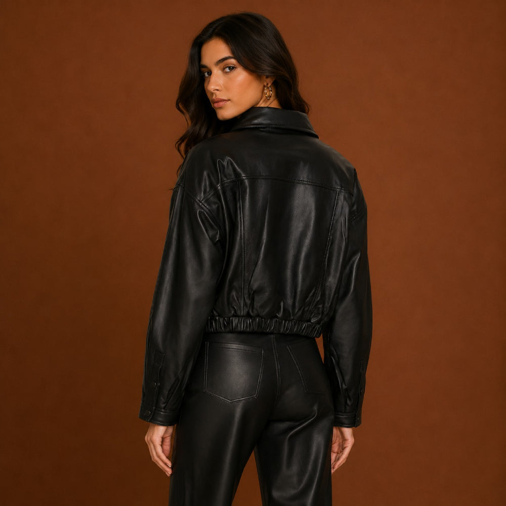 Person wearing a black leather jacket and pants against a brown background