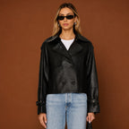 Woman wearing a black leather jacket and blue jeans against a brown background