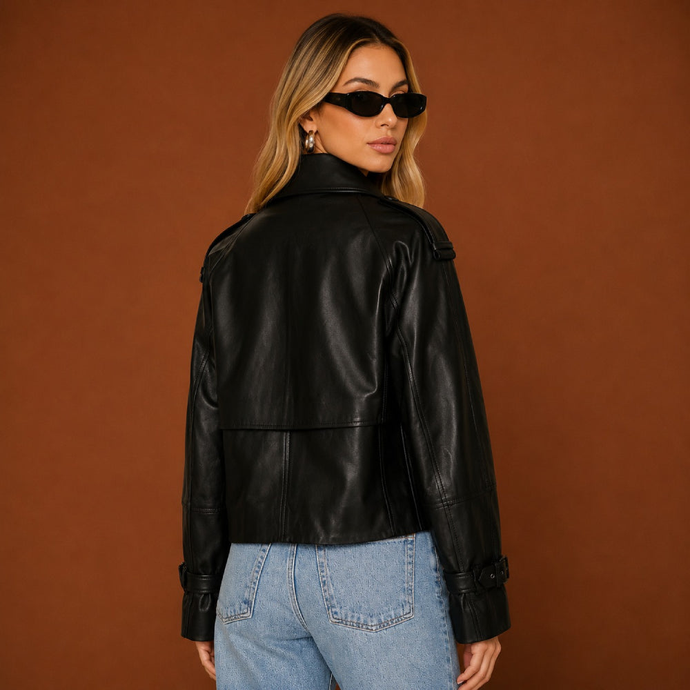 Woman wearing a black leather jacket and blue jeans against a brown background