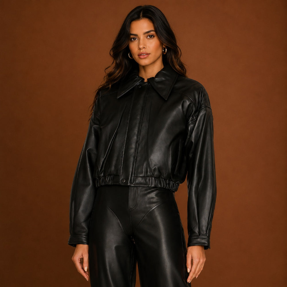 Person wearing a black leather jacket and pants against a brown background