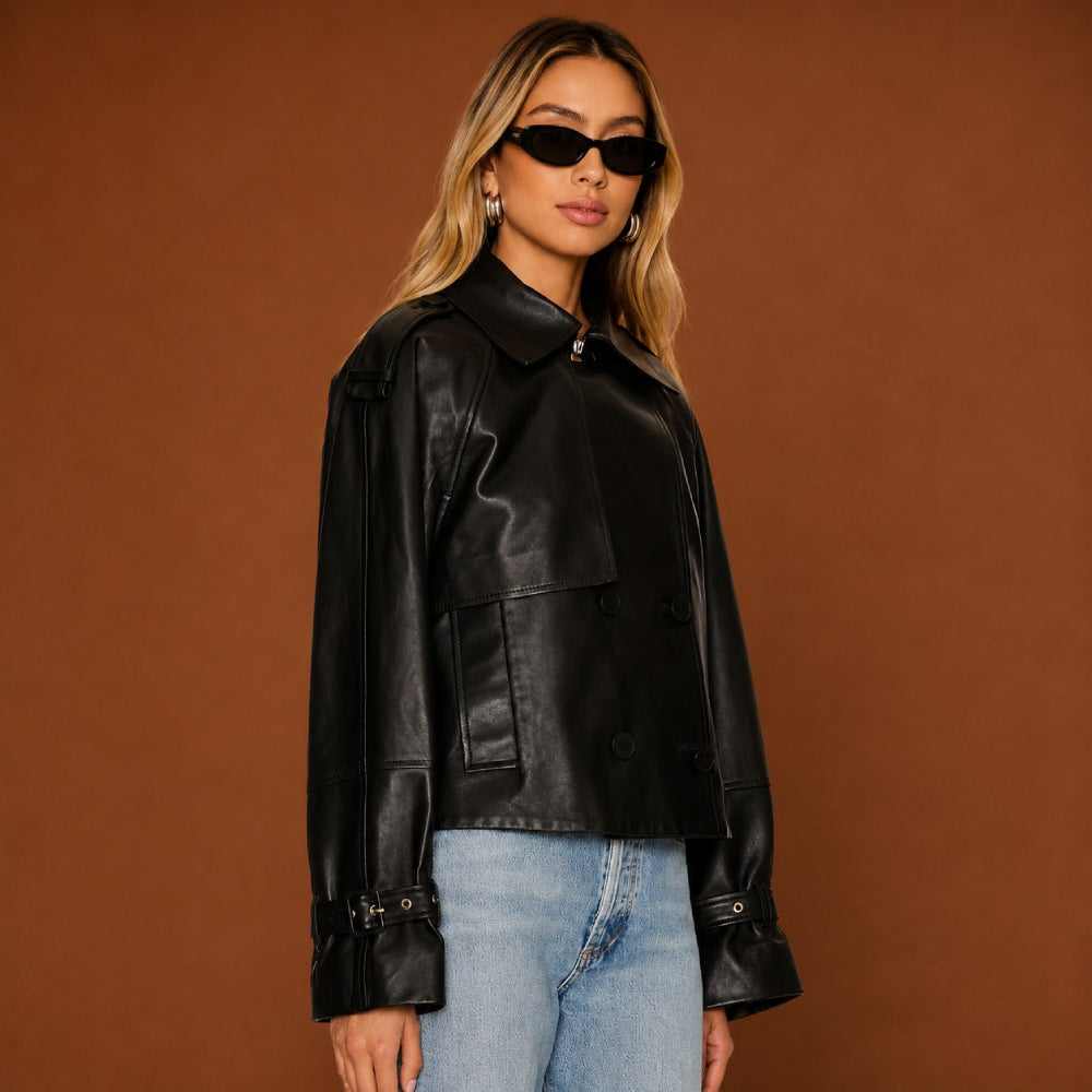 Woman wearing a black leather jacket and blue jeans against a brown background