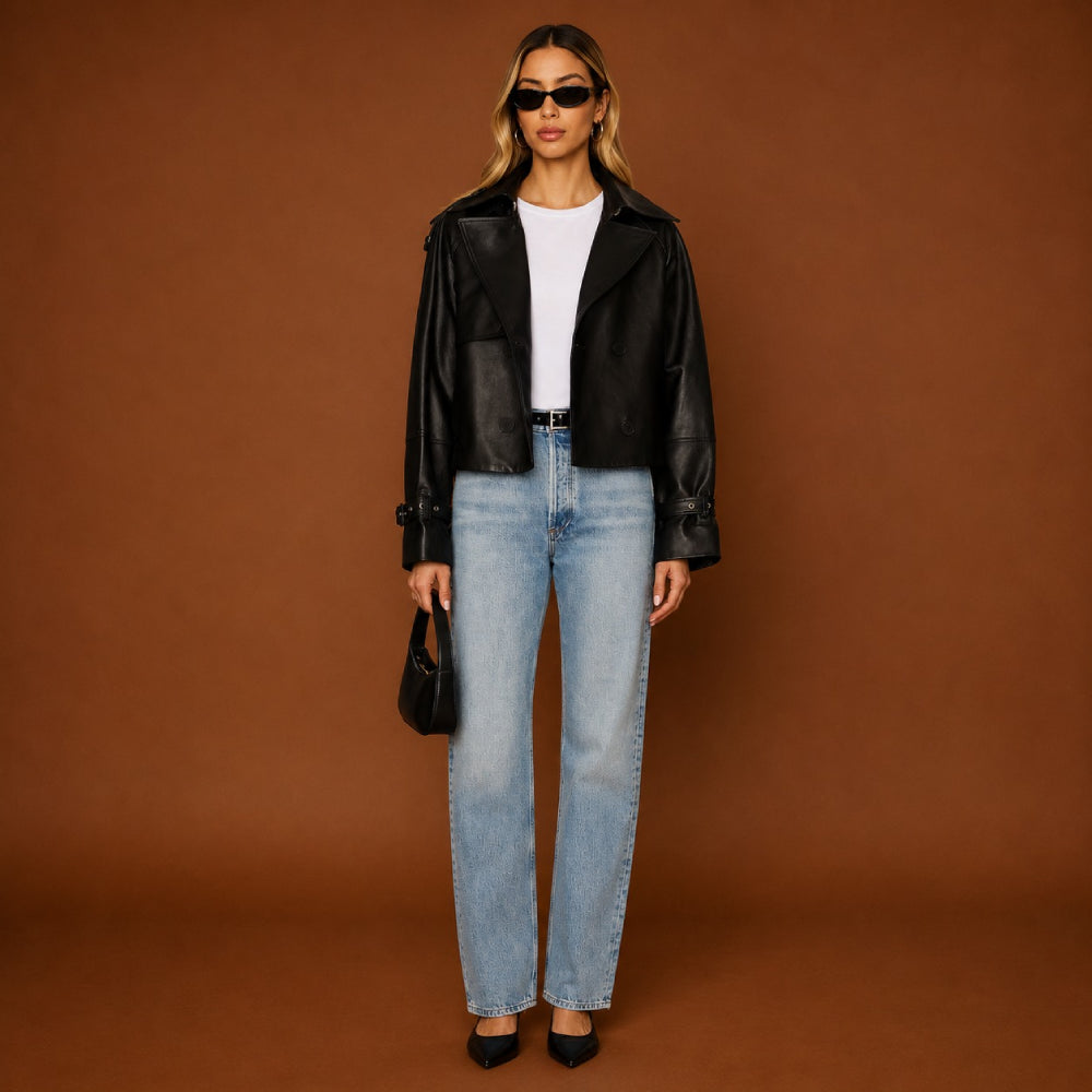 Woman wearing a black leather jacket, white shirt, blue jeans, and sunglasses on a brown background
