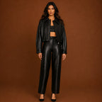 Woman wearing a black leather jacket and pants on a brown background