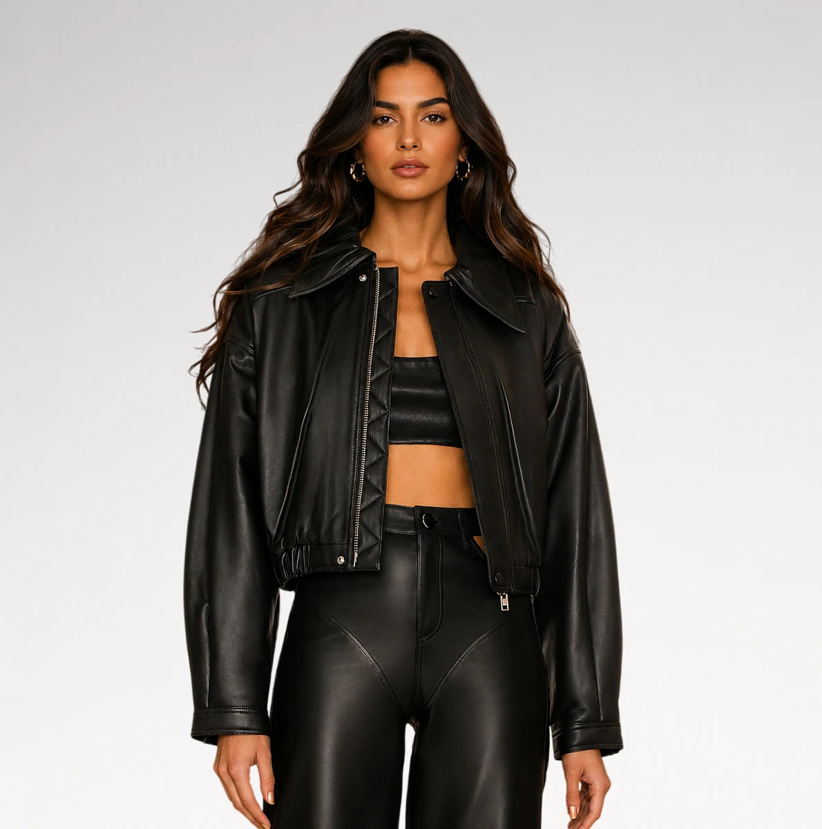 A woman modeling a black faux leather moto jacket, matching black crop top, and black faux leather pants against a light gray studio background. Main image