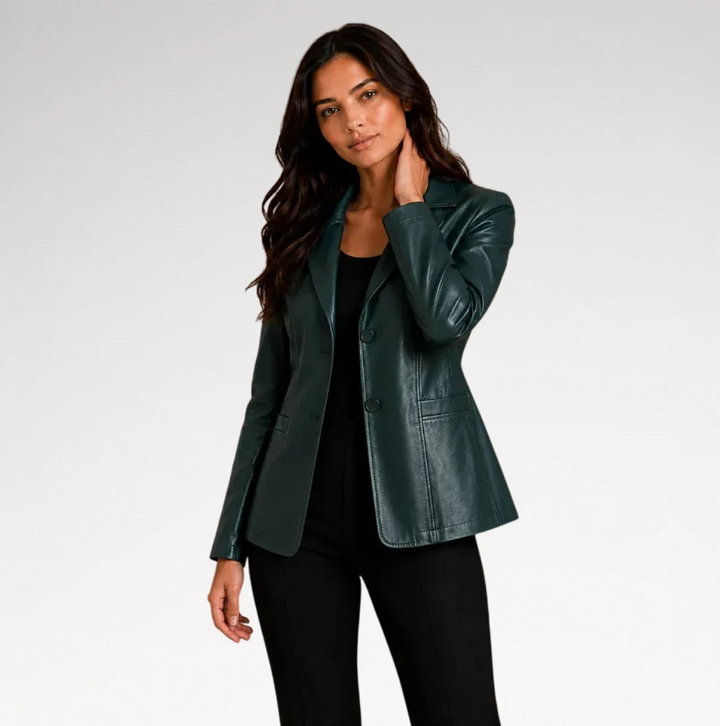 A woman modeling a dark green faux leather blazer over a black top and black pants, photographed against a light gray studio background.